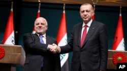 Iraq's Prime Minister Haider al-Abadi, left, shakes hands with Turkey's President Recep Tayyip Erdogan, following a joint news conference after their meeting at the Presidential Palace in Ankara, Turkey, Aug. 14, 2018.