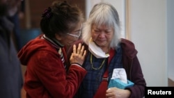 A woman comforts Colleen Love, right, who lost her home in the Camp Fire, at a "Thanksgiving Together" dinner put on by World Central Kitchen at Chico State University in Chico, California, Nov. 22, 2018.