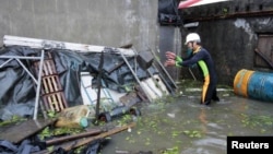 Seorang warga Wujie di Ilan County, Taiwan, berupaya membersihkan puing-puing yang berserakan di dekat rumahnya yang dilanda banjir. Topan Saola disertai hujan lebat menimbulkan tanah longsor dan melumpuhkan hampir seluruh Taiwan (2/8).