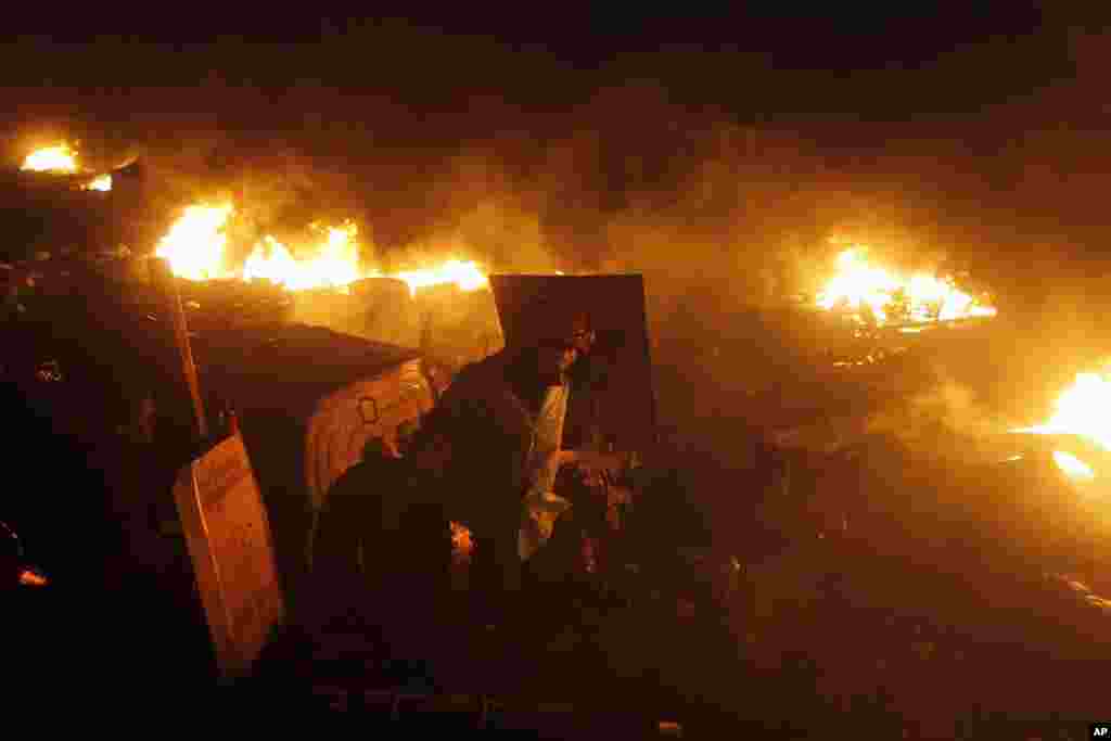 An anti-government protester prepares to throw a car tire into the flames lit by protesters at Independence Square in Kiev, Ukraine, Thursday, Feb. 20, 2014. Ukraine's protest leaders and the president they aim to oust called a truce Wednesday, just hours