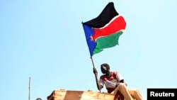 Seorang pria melambaikan bendera Sudan Selatan saat ia merayakan hasil referendum di kota Abyei, Oktober 2013. (Reuters/Goran Tomasevic)