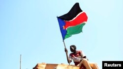 FILE - A man waves a South Sudanese flag in the town of Abyei, October 31, 2013. 