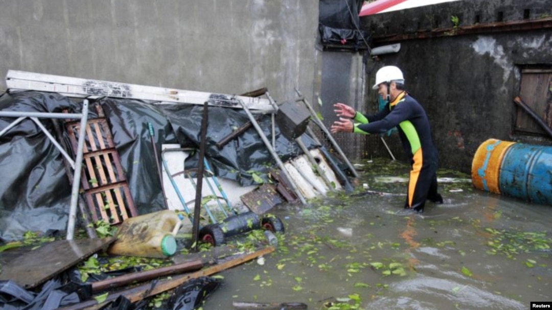 Seorang warga Wujie di Ilan County, Taiwan, berupaya membersihkan puing-puing yang berserakan di dekat rumahnya yang dilanda banjir. Topan Saola disertai hujan lebat menimbulkan tanah longsor dan melumpuhkan hampir seluruh Taiwan (2/8).