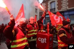 Firefighters hold flares during a protest in Rennes, western France, Dec. 17, 2019.