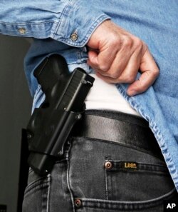 FILE - Hank Johnson displays his handgun, in Springboro, Ohio, Feb. 27, 2013.