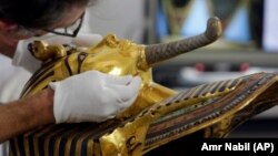 German restorer Christian Eckmann begins restoration work on the golden mask of King Tutankhamun over a year after the beard was accidentally broken off and hastily glued back with epoxy, at the Egyptian Museum in Cairo, Egypt, Tuesday, Oct. 20, 2015. The