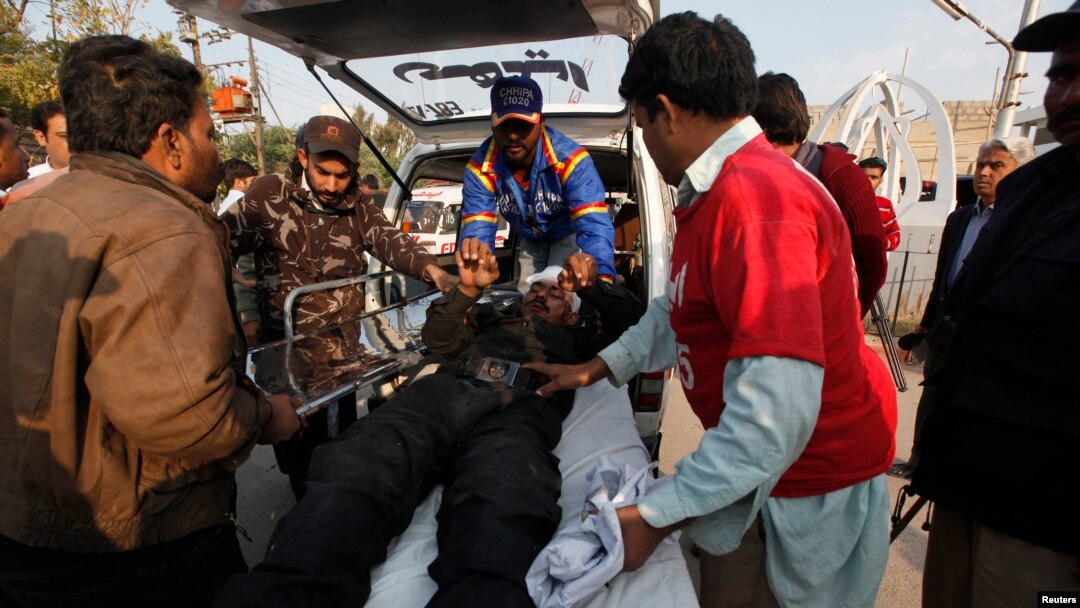 Petugas membawa seorang polisi yang terluka akibat serangan bom di sebuah bus ke rumah sakit "Jinnah Postgraduate Medical Centre" di Karachi (13/2).