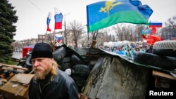 Pro-Russian supporters and an Orthodox priest (front) stand next to a barricade in front of the seized office of the SBU state security service in Luhansk, in eastern Ukraine on April 11, 2014. 