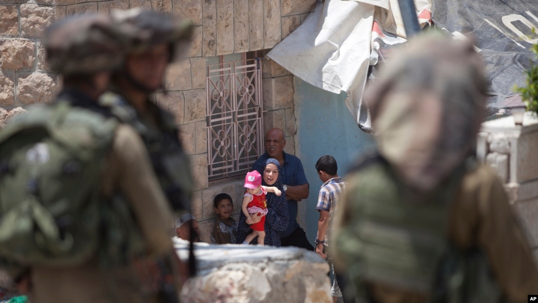 Tentara Israel berjaga-jaga dekat sebuah keluarga Palestina di luar rumah mereka dalam pencarian terhadap tiga remaja yang diculik di Hebron, Tepi Barat (18/6). (AP/Majdi Mohammed)