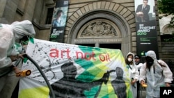 Campaigners dressed as a mock clean-up crew called the 'Greenwash Guerrillas' hold a banner outside the National Portrait Gallery in London, Tuesday, June 22, 2010, where the BP Portrait Award ceremony is held.