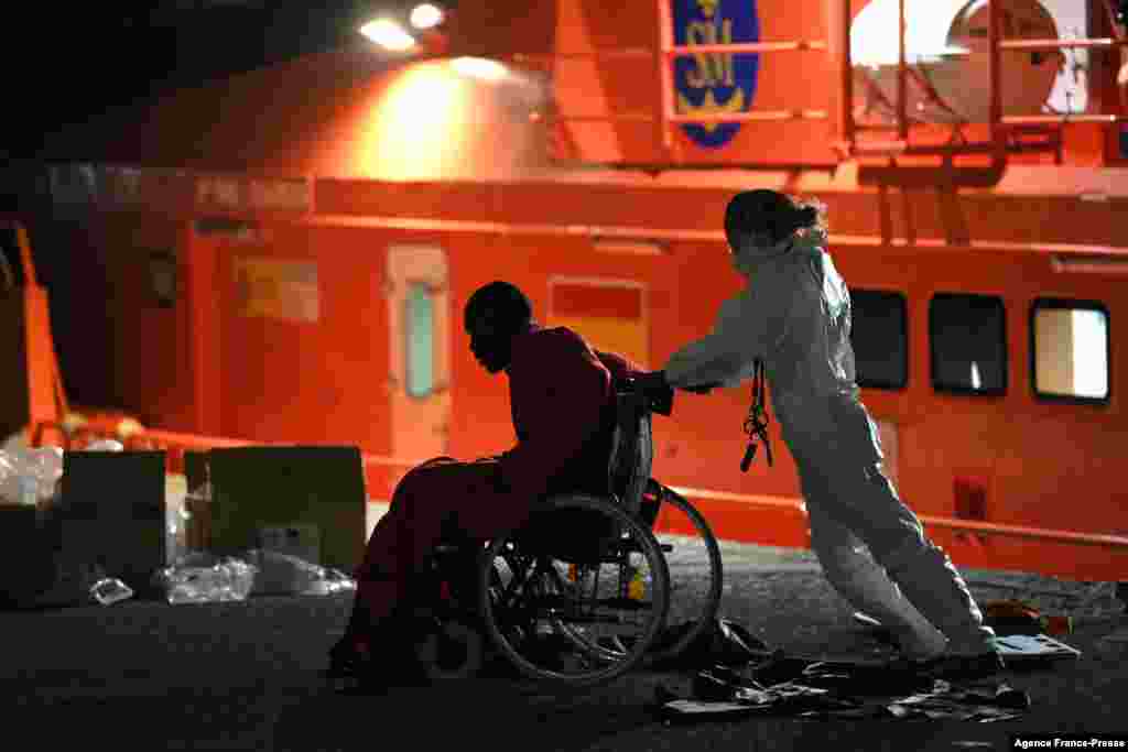 An emergency worker pushes a migrant in a wheelchair, in the port of Arguineguin, after a rescue operation off the coast of the Canary island of Gran Canaria, Spain.