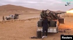 FILE - A still image taken on December 11, 2016 from a video released by Islamic State-affiliated Amaq news agency on Dec. 10, 2016, purports to show Islamic State fighters advancing over the Hayan mountain south of Palmyra.