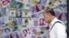 FILE - A man walks past an advertisement promoting China's renminbi (RMB) or yuan, U.S. dollar and Euro exchange services at foreign exchange store in Hong Kong, China, Aug. 13, 2015.