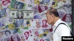 FILE - A man walks past an advertisement promoting China's renminbi (RMB) or yuan, U.S. dollar and Euro exchange services at foreign exchange store in Hong Kong, China, Aug. 13, 2015.