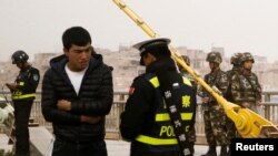 지난해 중국 서부의 신장 자치구에서 경찰이 위구르족 남성의 신원을 확인하고 있다. 