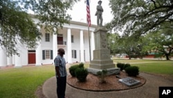 In this Aug. 1, 2018 photo, Ronnie Anderson, an African-American man charged with possession of a firearm by a convicted felon, waits next to a confederate statue on the lawn of the East Feliciana Parish Courthouse in Clinton, La.
