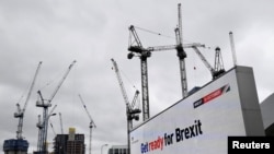 An electronic billboard displaying a British government Brexit information awareness campaign advertisement is seen near construction cranes in London.