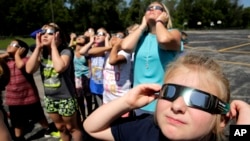 Alumnos de cuarto grado de una escuela de Kansas City practican el uso correcto de anteojos protectores para ver el eclipse de este lunes.