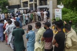 People queue up and wait to get themselves inoculated with the Covid-19 coronavirus vaccine at a vaccination centre in Karachi on August 1, 2021. (Photo by Rizwan TABASSUM / AFP)