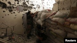 Free Syrian Army fighters take their positions behind piled sandbags, as one of them points his weapon, from inside a room in Deir al-Zor, Sept. 2, 2013. 