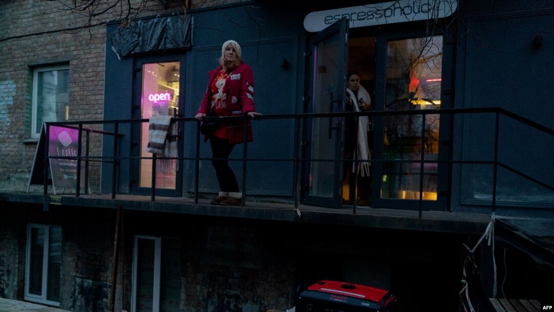 A woman stands on a balcony above an electric generator during a partial blackout in Kyiv, Ukraine, on Nov. 28, 2024, following Russian strikes on Ukrainian energy infrastructure.