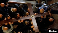 Worshippers carry a large wooden cross into the Church of the Holy Sepulchre during Good Friday procession along the Via Dolorosa in Jerusalem's Old City, April 19, 2019.