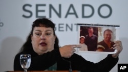 Gloria Alejandro Paulik muestra una foto de su padre, víctima de terrorismo, en un acto en el Congreso en homenaje a las víctimas del terrorismo, en Buenos Aires, Argentina, el 27 de agosto de 2024