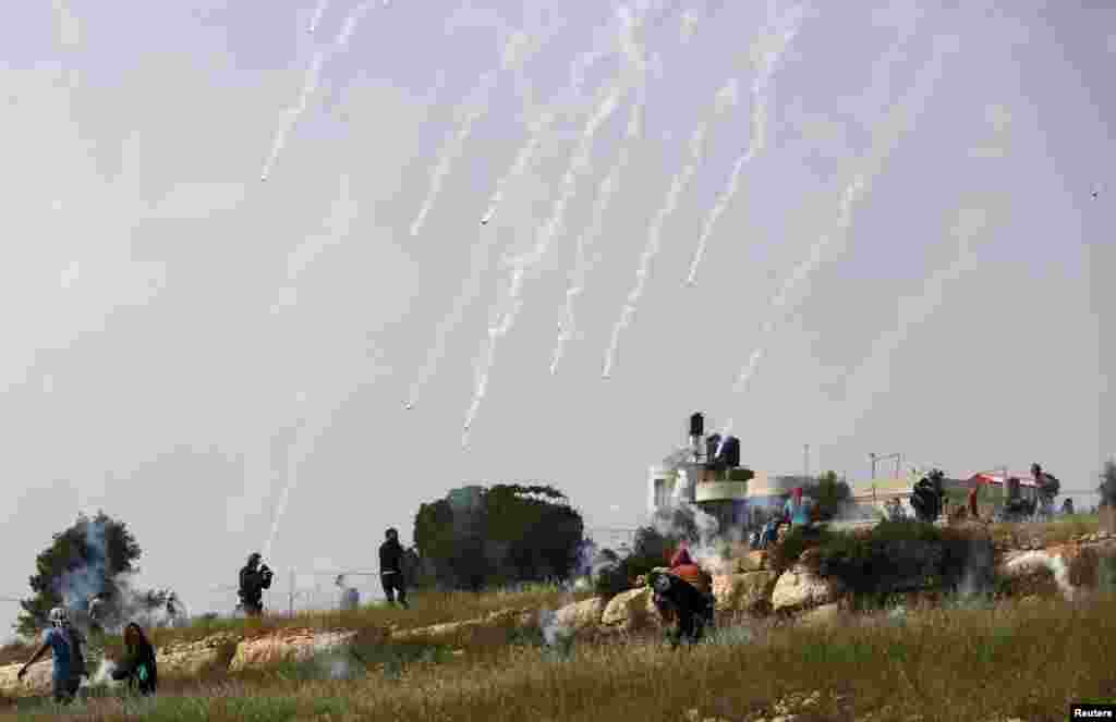 Palestinian protesters run from tear gas canisters launched by Israeli troops during clashes following a protest marking Land Day in the West Bank village of Nabi Saleh near Ramallah, March 28, 2015. Palestinians mark Land Day on March 30, the annual commemoration of protests in 1976 against Israel&#39;s appropriation of Arab-owned land in the Galilee.