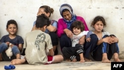 Mabrouka (à gauche), sa sœur Meriam et les enfants de leurs familles, sont assis devant leur maison, dans un quartier populaire de la ville portuaire de Sfax, dans l'est de la Tunisie, le 11 septembre 2020.