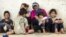 Mabrouka (à gauche), sa sœur Meriam et les enfants de leurs familles, sont assis devant leur maison, dans un quartier populaire de la ville portuaire de Sfax, dans l'est de la Tunisie, le 11 septembre 2020.