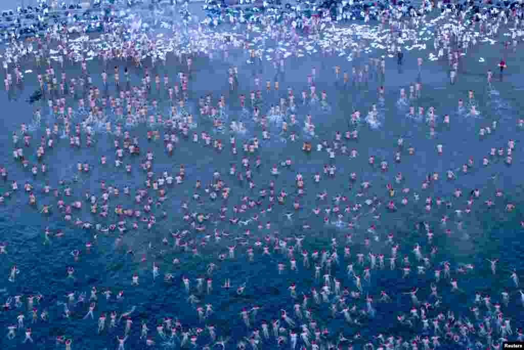 Participants of the Dark Mofo Nude Solstice Swim are seen in the River Derwent at dawn, in Hobart, Australia. (Courtesy: AAP/Rob Blakers/via REUTERS)