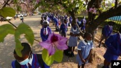 Schoolchildren wait to enter their school in Harare, Zimbabwe, Monday Sept, 28, 2020. Zimbabwe schools have reopened in phases, but with smaller number of pupils, more teachers and other related measures to enable children to resume their education withou