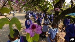 File- Schoolchildren wait to enter their school in Harare, Zimbabwe, Monday Sept, 28, 2020. 