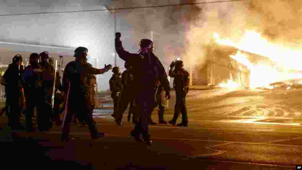 Police guard the area as some buildings are set on fire after the announcement of the grand jury decision, in Ferguson, Missouri, Nov. 24, 2014.