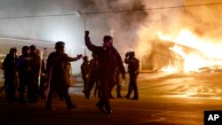 Police guard the area as some buildings are set on fire after the announcement of the grand jury decision, in Ferguson, Missouri, Nov. 24, 2014. (AP Photo/David Goldman) 