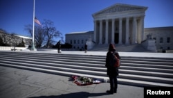 FILE - Flowers are seen as a woman stands in front of the Supreme Court building in Washington D.C. after the death of U.S. Supreme Court Justice Antonin Scalia, Feb. 14, 2016. Many Senate Republicans say Obama, a Democrat, should not nominate someone to fill Scalia's seat.