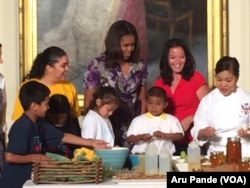 Michelle Obama, center, and Deb Eschmeyer, second from right, head of "Let's Move!" program, join kids in making salads from products out of the garden planted on the South Lawn of the White House earlier this year, June 3, 2015.er this year.