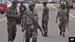 File - Nigerian soldiers patrol the area near the scene of a shopping mall explosion in Abuja, Nigeria, June 25, 2014.