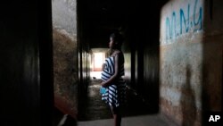 Tanaka Rwizi, a pregnant 16 year old teenager mother, stands in the hallway of her residence in the poverty stricken Mbare township in Harare, Zimbabwe, Saturday Nov. 13, 2021. (AP Photo/Tsvangirayi Mukwazhi)