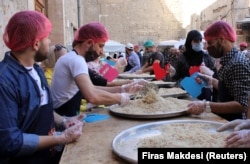 Relawan dari organisasi amal "Saed" menyiapkan makanan untuk dibagikan kepada orang-orang yang membutuhkan selama bulan suci Ramadhan, di Damaskus, Suriah, 23 April 2021. (Foto: REUTERS/Firas Makdesi)