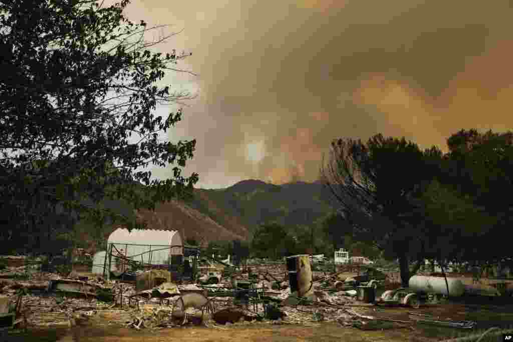 25일 미국 캘리포니아주 사우스레이크 산악지대에서 산불로 인한 연기가 솟아오르는 가운데, 타다남은 이동식 주택 잔해가 방치돼있다. &nbsp;