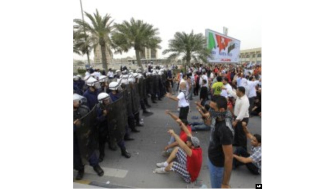 Anti-government protesters shout slogans at riot policemen as they block a road in Manama, Bahrain, March 13, 2011