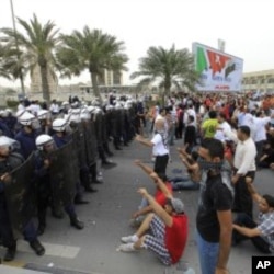 Anti-government protesters shout slogans at riot policemen as they block a road in Manama, Bahrain, March 13, 2011