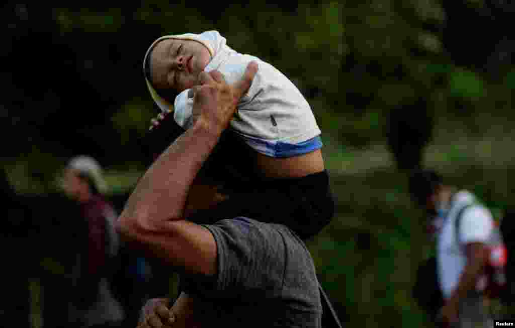 A Honduran migrant carries a boy on his shoulders, as they take part in a caravan heading to Mexico City, in Acacoyagua, Mexico Oct. 29, 2021.