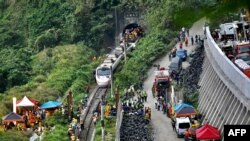 Para petugas penyelamat berada di lokasi kecelakaan kereta yang tergelincir ketika keluar terowongan, Jumat (2/4).