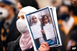 FILE - Demonstrators hold images of Yemeni civilians who were barred from immigrating to the United States during an "I Want My Miracle Back" rally, in the Bronx borough of New York, March 24, 2021.