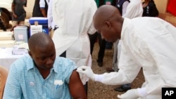 FILE - A health worker prepares to inject a man with an Ebola vaccine in Conakry, Guinea, March 7, 2015.