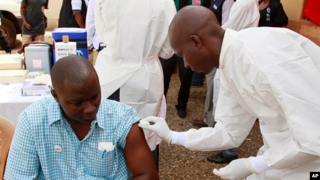 A health worker prepares to inject a man with an Ebola vaccine in Conakry, Guinea, March 7, 2015.
