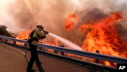 A firefighter battles a fire along the Ronald Reagan (118) Freeway in Simi Valley, California, Nov. 12, 2018.