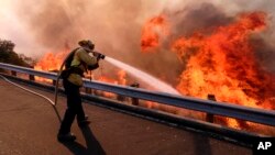 加州一名消防員在118號高速公路上向山火噴水（2018年11月12日）